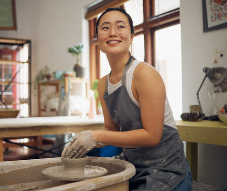 Pottery, thinking and creative with an asian woman using a wheel for the design of an art of ceramic...