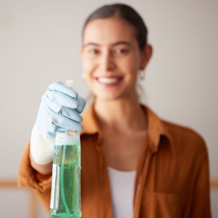 Woman, spray bottle and cleaning service with a smile in a house or apartment for safety with gloves...