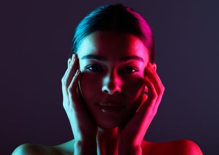 Beauty, neon shadow light and portrait of woman with dark lighting, facial cosmetics and skincare glow. Luxury studio makeup, aesthetic creativity and face model with creative pink blue color designの写真素材