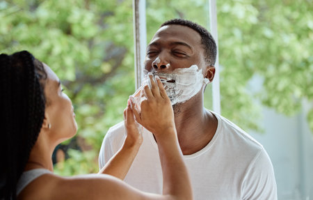 Black couple with shaving foam, morning hygiene in home bathroom and skincare product for facial treatment. Beauty wellness for cleaning face, happy boyfriend or natural cosmetics cream applicationの写真素材