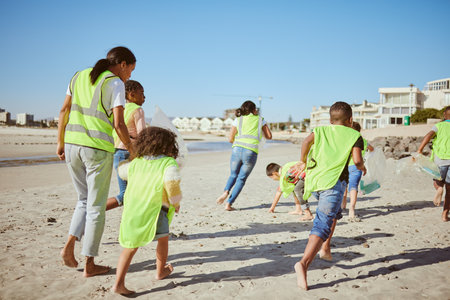 Woman and group of children cleaning beach for volunteering, community and charity with earth day, climate change and education. Friends, teacher volunteer and recycle plastic for pollution learningの写真素材