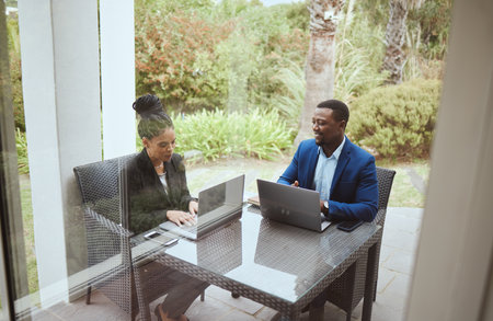 Business people, man and black woman in meeting on terrace, laptop and finance goal on business trip. Black man, woman and teamwork in morning business meeting on patio, hotel or garden for planningの写真素材