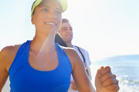 Running with a loved one. A young couple running together at the coast.の写真素材