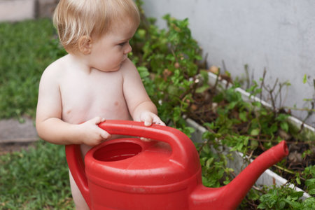 Curious about how nature works. An adorable baby boy watering the garden.の写真素材