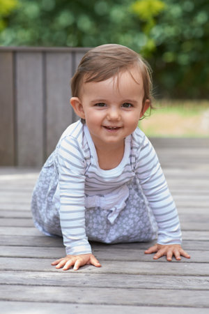 Shes a curious little one. Portrait of a cute little baby crawling around on a patio deck.
