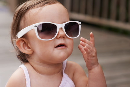 Loving Fashion from a young age. An adorable baby girl wearing oversized sunglasses outside.の写真素材