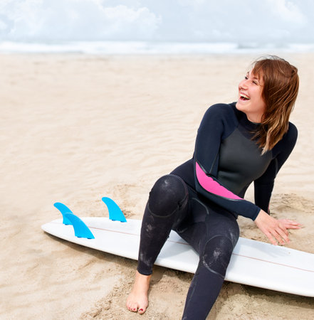 She cant wait to hit the water. A young female surfer getting ready to go out and enjoy the waves on a hot summers day.の写真素材