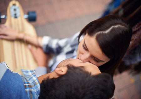 Kissing break from skateboarding. High angle shot of a couple of skateboarders kissiing.の写真素材