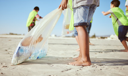 Children, legs or plastic bottles in beach clean up, climate change collection or environment sustainability recycling. Kids, diversity or students in cleaning waste management or community serviceの写真素材