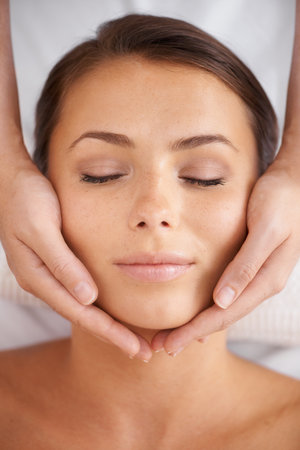 Getting in the right head space. High-angle view of a young woman lying in a spa receiving a head massage.の写真素材