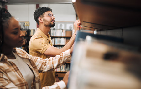 Library, student and books of a man reading book information for college research. School, learn and study knowledge of students ready for studying, learning and campus scholarship educationの写真素材