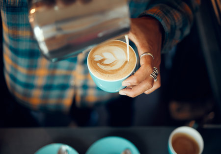 Coffee, milk and hands of man in cafe for cappuccino, breakfast and caffeine beverage. Relax, espresso and dairy with barista in coffee shop with latte art for retail, mocha and drink preparationの写真素材