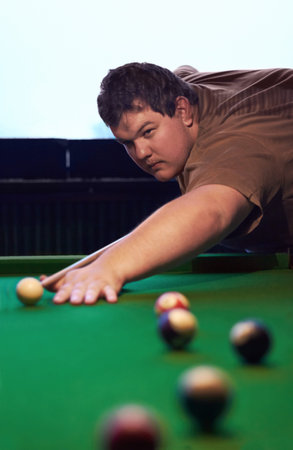 Taking the winning shot...A young man playing a game of pool.