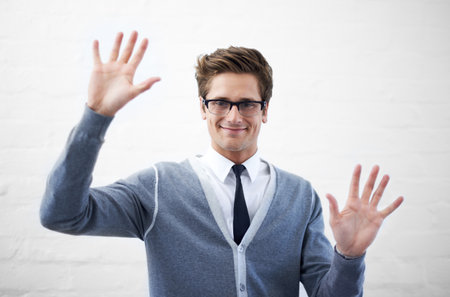 Touchscreen technology is the future. A handsome young nerdy guy with open palms as if touching something virtual.の写真素材