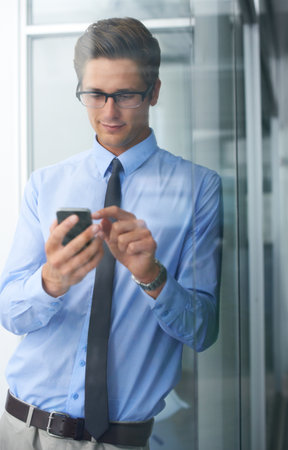 Sending a quick text message. A young entrepreneur sending a text message.の写真素材