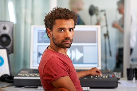 Taking time to perfect the recording...A handsome young sound engineer sitting in front of his...