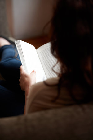 Enjoying a good read. A rearview shot of a young woman reading a book.