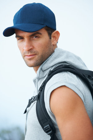 He has an adventurous glint in his eyes...Handsome young hiker wearing a baseball cap looking...