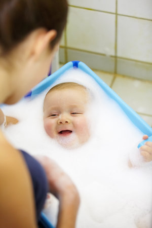 This is fun. Laughing baby boy getting a soapy foam bath from his mom.
