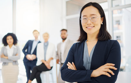 Portrait of a confident young asian businesswoman wearing glasses and standing with her arms crossed...