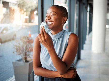 Young cheerful African american businesswoman removing her mask while at work. One happy black female businessperson taking off her mask protecting from virus while on a break at workの写真素材