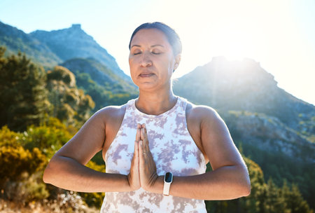 Mature woman meditating with joined hands and closed eyes breathing deeply. Finding inner peace, balance and living healthyの写真素材