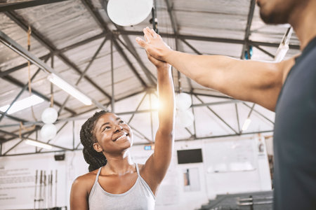 Happy friends high five after a workout. Young trainer motivating his client to exercise. African...