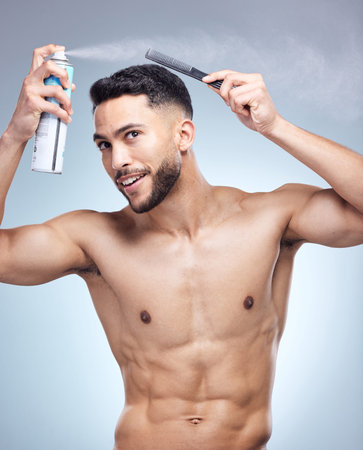 He never leaves without his products. a young man combing his hair against studio background.