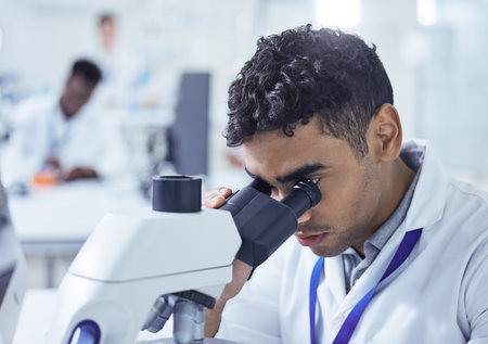 Hes onto the next mission. a young male lab technician using a microscope.