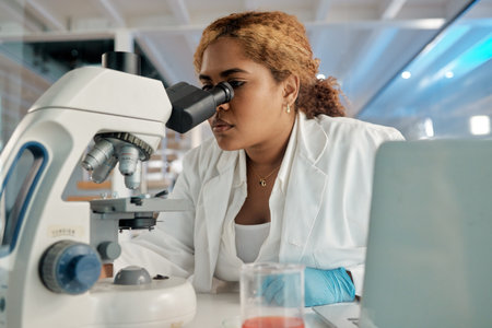 Looking with hawk like precision. a young female lab worker analysing samples through a microscope.