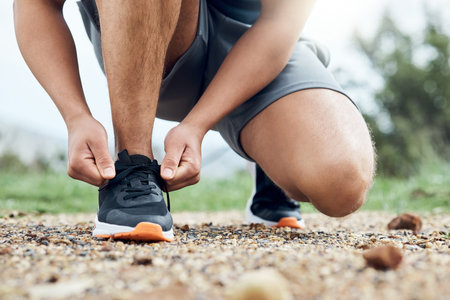 You cant go running with uncomfortable shoes. an athletic man tying his laces while our for a run.