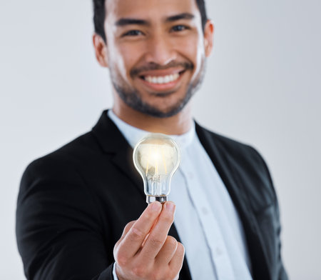 .a young man holding a light bulb against a grey background.の写真素材
