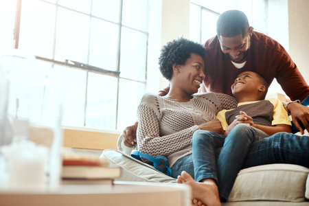 Black family, happy and relax on sofa with boy and parents, hug and laughing in their home together. Happy family, mother and father playing with their son on a couch, content and joy in living roomの写真素材