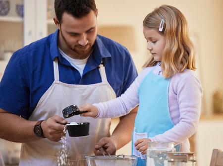 One level cup of flour. a young father helping his daughter measure out flour.の写真素材