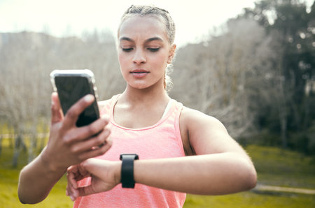 Comparing my heart rate data. an attractive young woman standing alone and using her cellphone while...