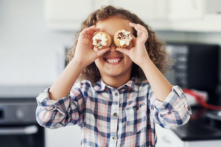Look, Im a spy. a playful little girl having fun while baking in the kitchen at home.の写真素材