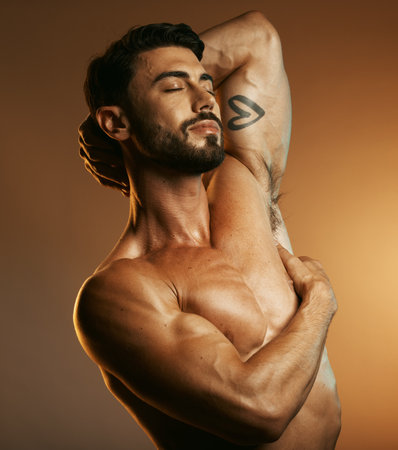 Beauty, body fitness and man in studio isolated on a brown background. Eyes closed, exercise and topless male model or bodybuilder with muscles feeling satisfied after training for health or wellnessの写真素材