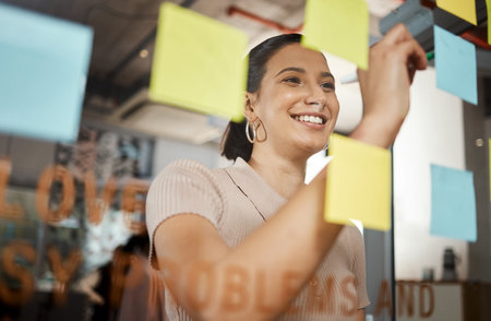 Success belongs to those who plan for it. a businesswoman brainstorming with sticky notes on a glass...