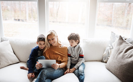 Tablet, home and mother with children on sofa bonding, quality time and relax on weekend together. Love, family and mom and kids with digital tech for online games, streaming movies and internet appの写真素材