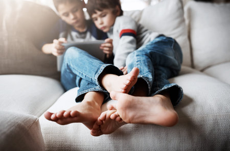 Boy siblings, tablet and sofa to relax with digital app for learning, gaming or web streaming movie....