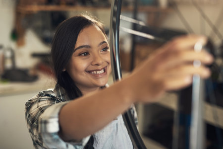 Oh, that wheel turns alright. a young woman woking at a bicycle repair shop.の写真素材