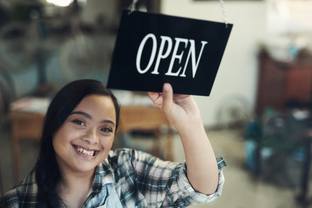 Another day, another life. Portrait of a young woman turning an open sign at work.