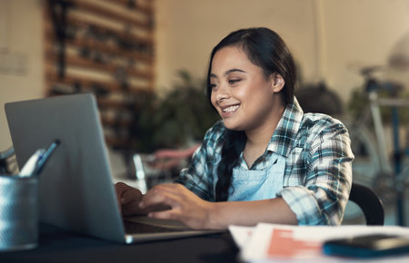 Crack a brief smile. a young woman using a laptop at work.の写真素材