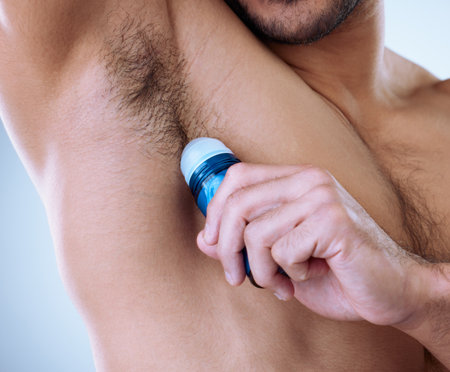 Full day of protection. Cropped studio shot of an unrecognizable man applying deodorant.の写真素材