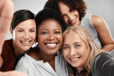 Smile for the camera. a diverse group of women standing close together in the studio and take a selfie.の写真素材