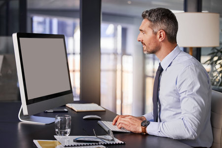 Work harder, then work harder. a businessman using his computer while sitting at his desk.