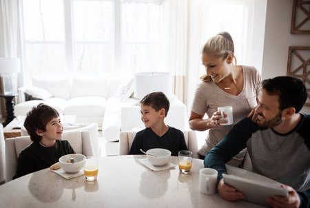 Family, children and breakfast with a mother, father and boy siblings sitting around a table in the morning. Kids, love or bonding with a son, brother and parents enjoying a meal in the home togetherの写真素材