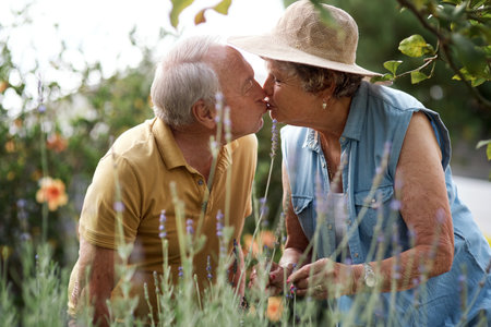 Slow motion with you, forevermore. an elderly couple sharing a kiss in their backyard.の写真素材