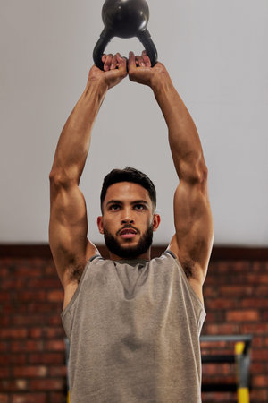 Winners keep going until they get it right. a young man working out with a kettle bell in a gym.