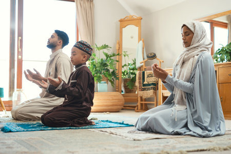 Our prayers do make a difference. a young muslim couple and their son praying in the lounge at home.の写真素材